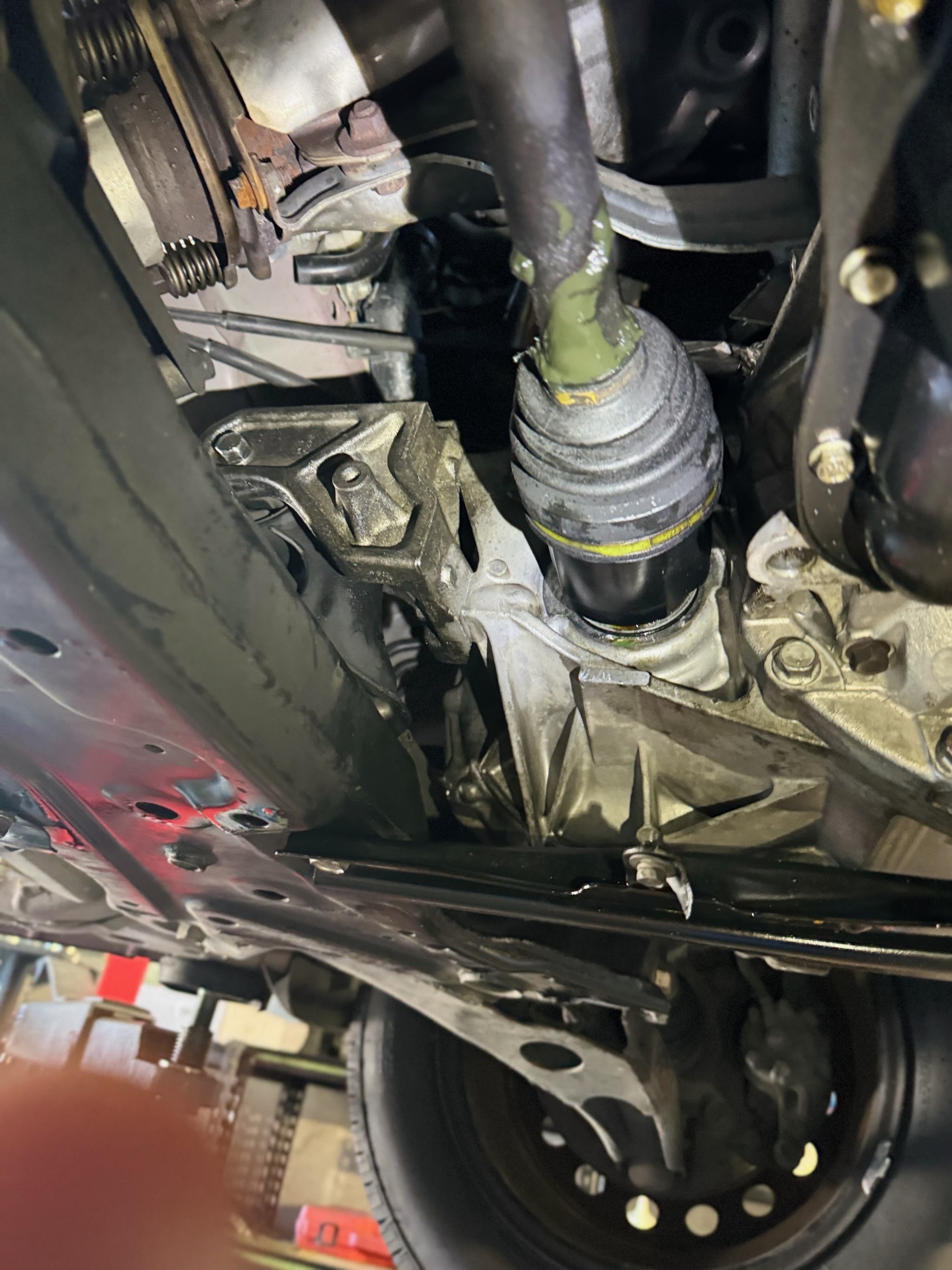 A freshly fitted CV joint boot and driveshaft underneath a car on the hoist